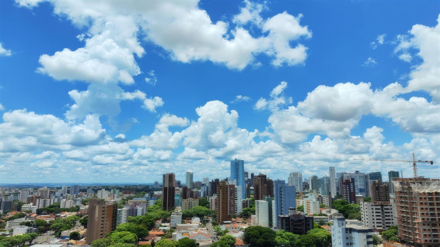 Maringá vista do alto, com prédios e árvores sob um céu de nuvens
